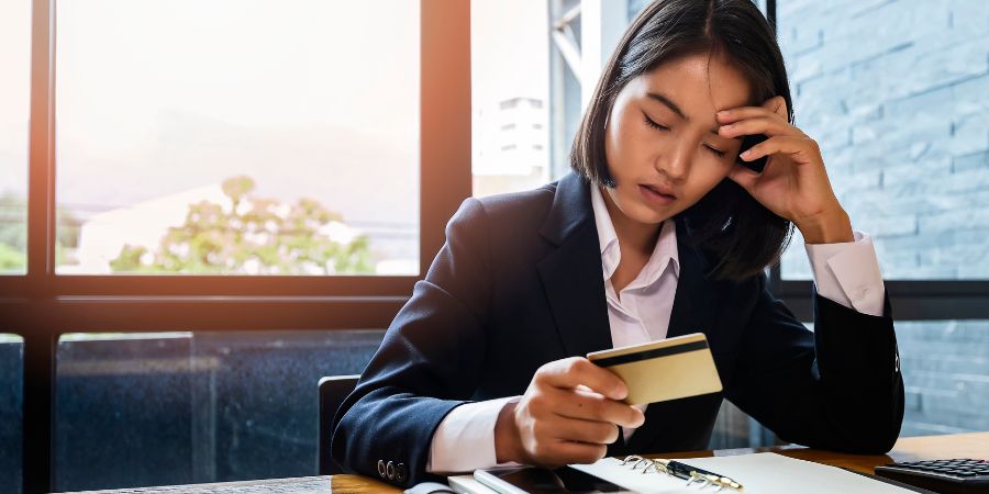 Protea Financial Effective Ways of Managing Business Debt asian woman looking at a credit card and being upset