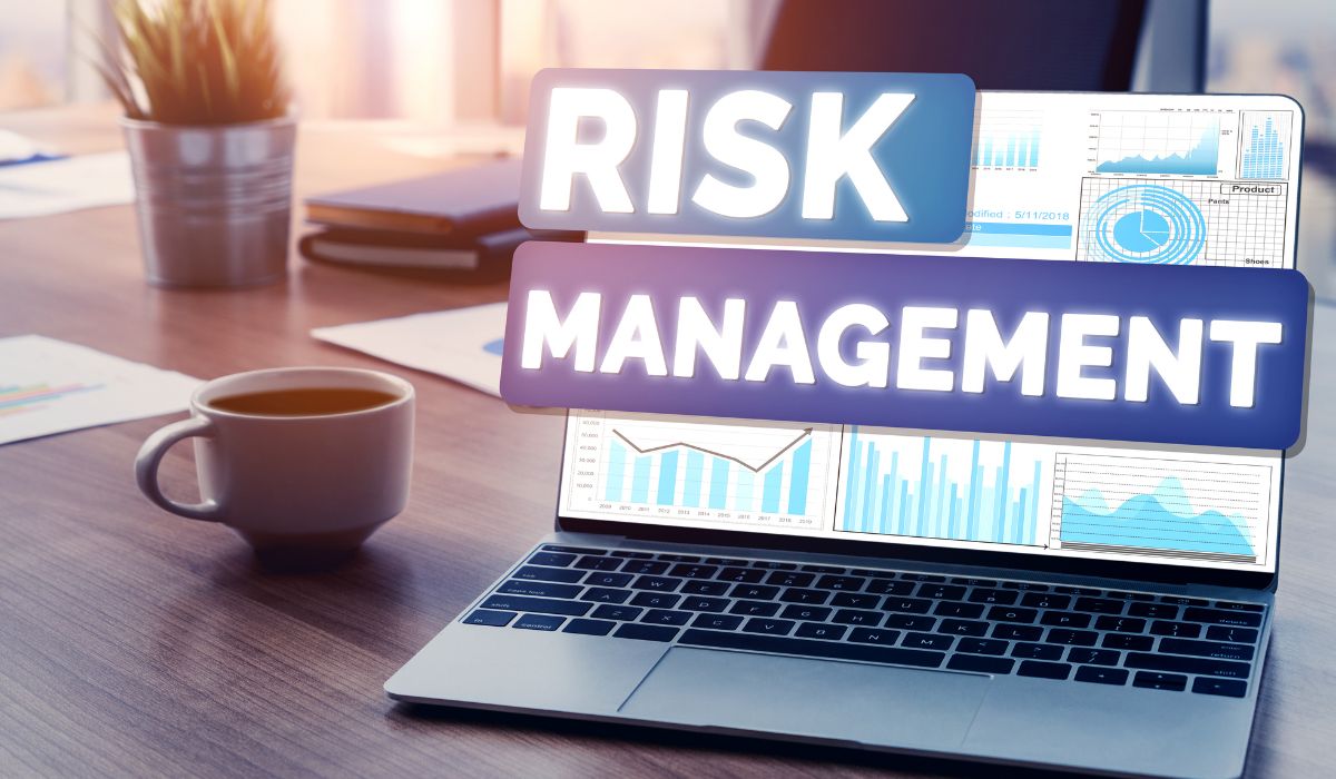 Protea Financial Risk management and Insurance laptop with graphs and the words risk management across the screen with a coffee cup in the background