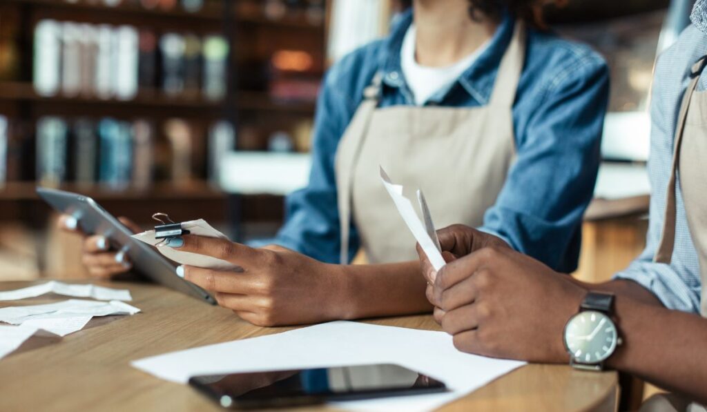 Protea Financial Accounting Tips for Small Business two owners reconciling their receipts at a table with a phone and paperwork