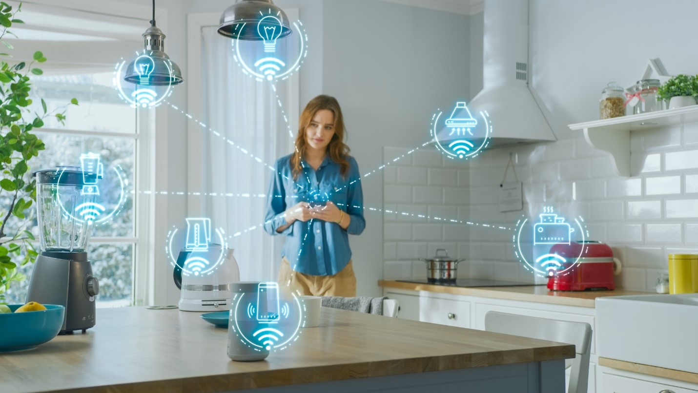 A person standing in a kitchen controlling devices via IoT