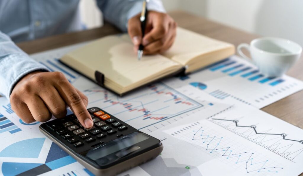 Protea Financial manual accounting vs tech driven accounting software person doing their accounting the traditional way with a pen and paper and calculator