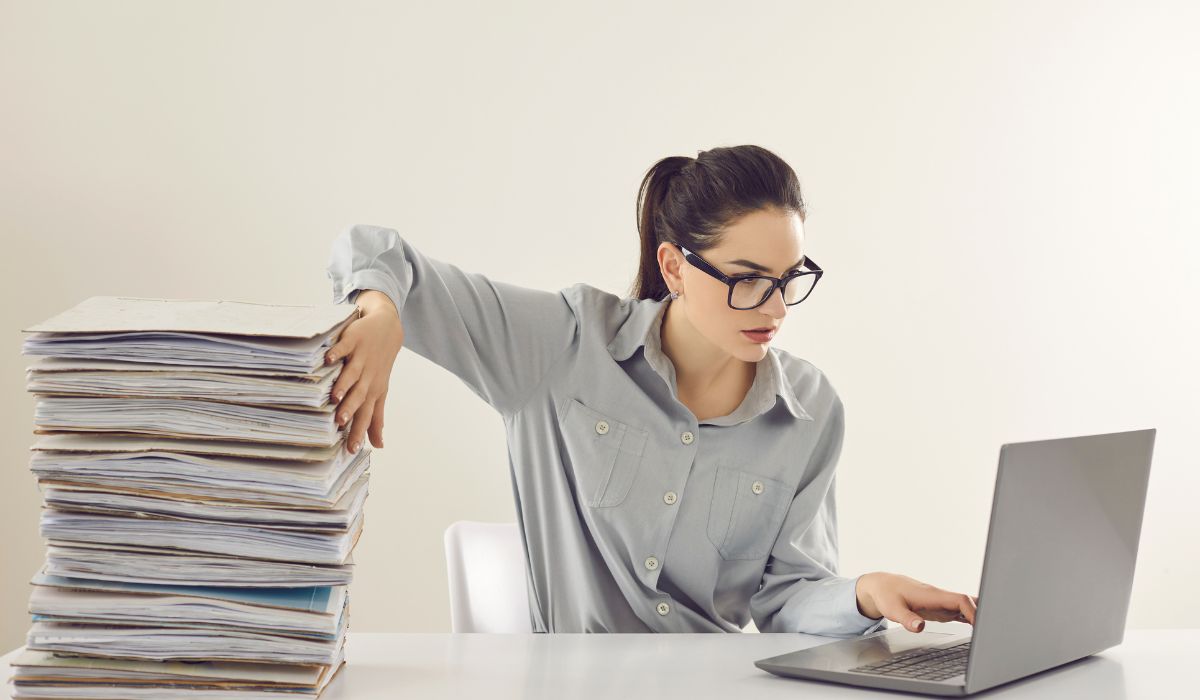 Protea Financial Woman choosing the right bookkeeping software for her business next to a pile of paperwork