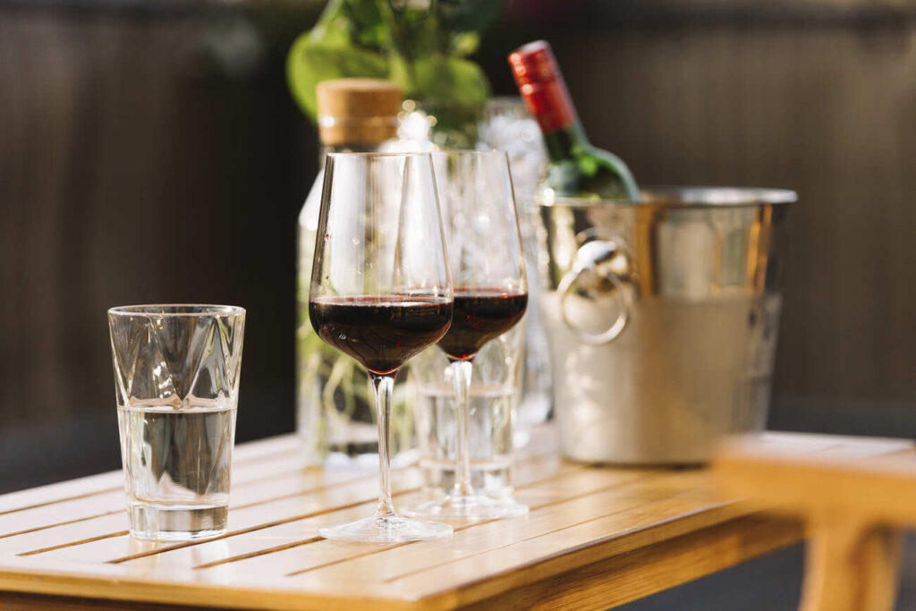 two red wine glasses glass water wooden table