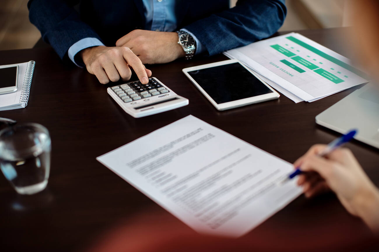 Bookeeper using calculator while his client is signing contract